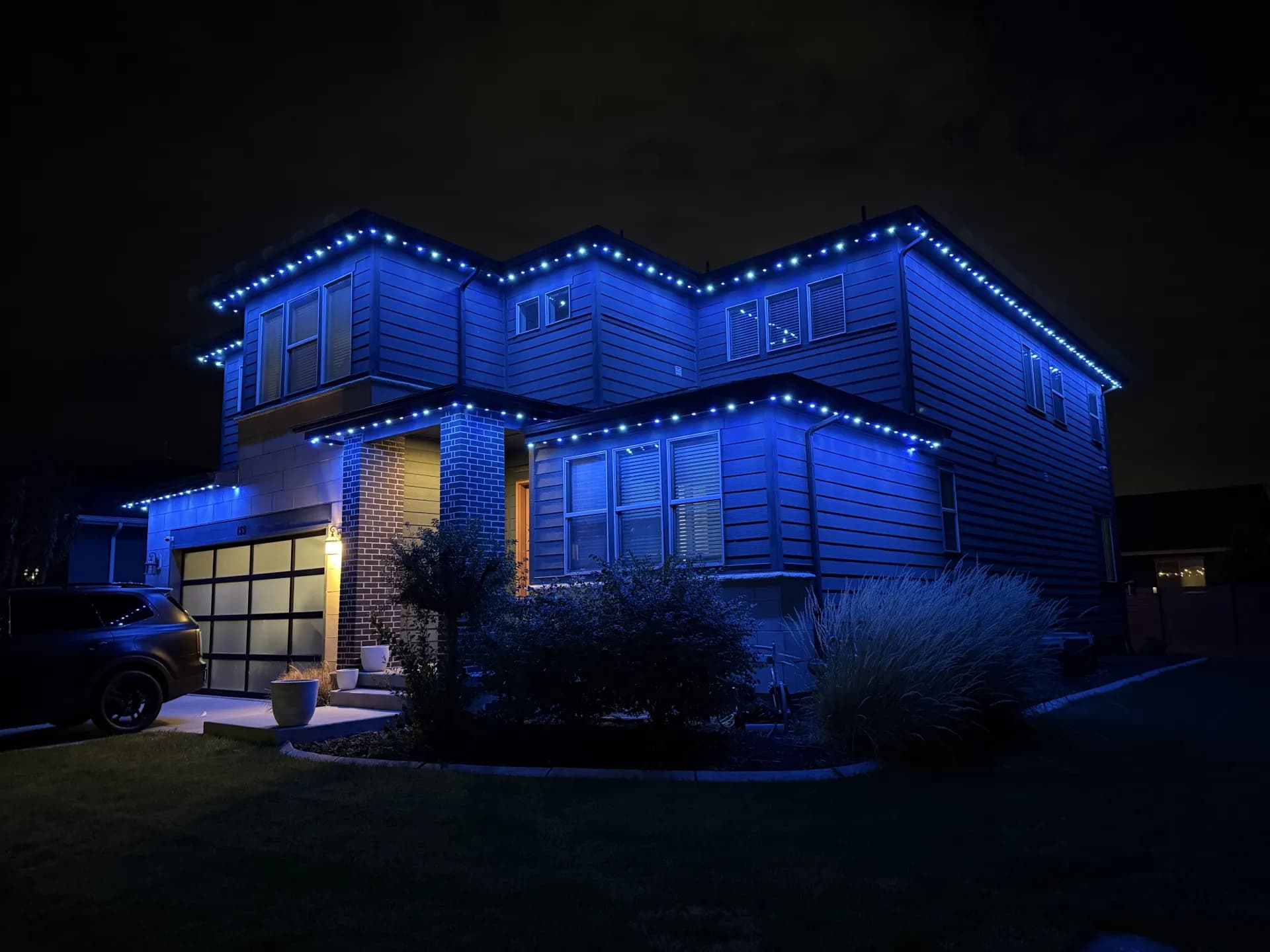 Farmhouse-style home with permanent LED accent lights at dusk